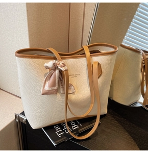 Close-up of beige tote bag with litchi texture, brown piping, and fashion silk scarf