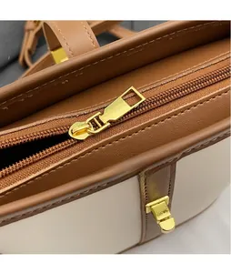 Close-up of golden zipper puller and fine stitching on brown leather handbag