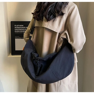 Macro detail of the black nylon crescent bag with adjustable buckle and zipper puller