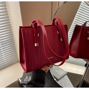 Detail of red bridal tote bag with wave-patterned texture and gold hardware details