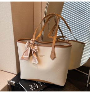 Detail of cream tote bag with lychee texture leather and decorative checkered scarf