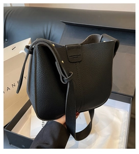 Gros plan du sac seau en cuir noir grainé avec détail du logo vintage embossé