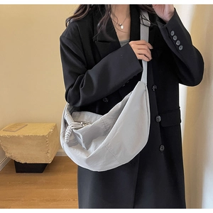 Detail of grey nylon crescent bag showing fabric texture and woven zipper pull on shoulder strap