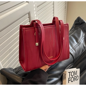 Detail view of red tote bag featuring wave textured leather and metallic hardware accents