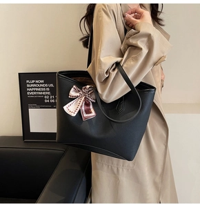 Detail of black pebbled leather tote bag featuring a geometric silk scarf accessory