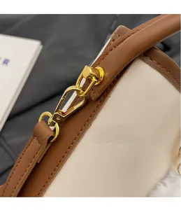 Detail of premium textured leather handbag featuring golden metal hook and brown trim