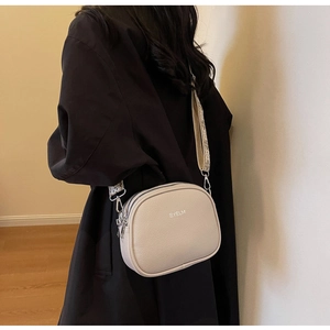 Detail of the BYELM cream leather crossbody bag featuring wide jacquard strap and dual zippers