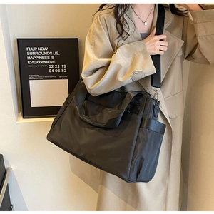 Détails de la bandoulière amovible et poche latérale du grand sac de voyage noir