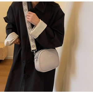 Close-up of beige lychee grain crossbody bag with wide jacquard strap and dual zippers