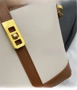 Detail of contrast leather shoulder bag with golden metallic lock and precise stitching