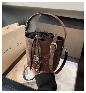 Détail du sac seau marron vintage avec logo argenté et fermeture à cordon coulissant