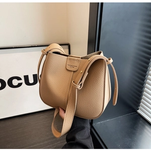 Détail du sac seau kaki en cuir grainé avec logo embossé et bandoulière assortie