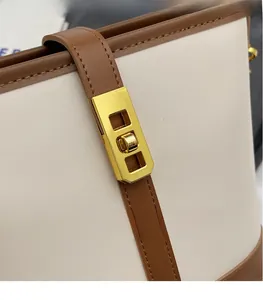 Detail showing high-quality golden turn-lock hardware on a beige litchi grain bucket bag