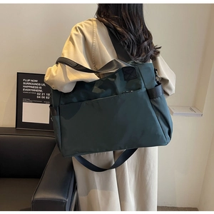 Détail d'un grand sac fourre-tout en nylon vert foncé avec poignées et poche avant
