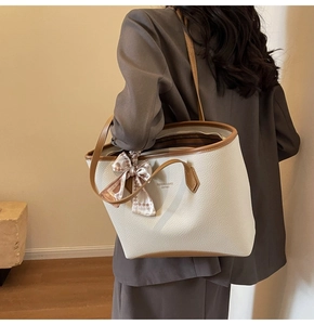 Detail of off-white tote bag with brown handles and a stylish checkerboard scarf