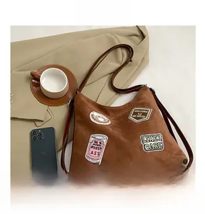 Detail view of brown suede tote bag with vintage embroidery and leather bottom trim