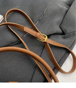 Detail of adjustable caramel leather shoulder strap with golden buckle and textured finish