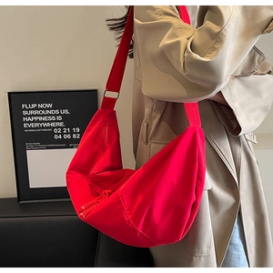 Close-up of red nylon crescent bag featuring wide shoulder strap and metal buckle