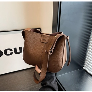 Détail du sac seau en cuir grainé marron foncé avec boucle métallique et logo mode