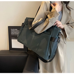Gros plan du sac fourre-tout en nylon vert foncé avec sangles tissées et poche latérale utile