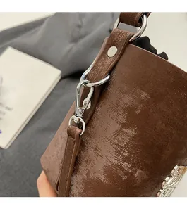 Gros plan détaillé du sac à main marron brillant avec logo métallique argenté