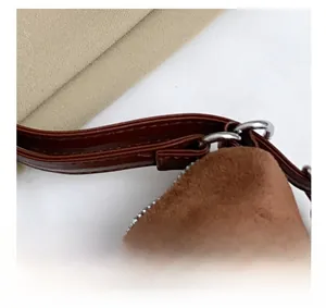 Detail shot of brown suede tote bag with silver metal ring and glossy leather strap