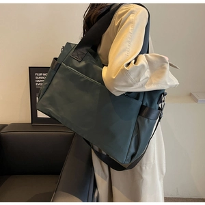 Sac de voyage en tissu Oxford vert foncé porté avec bandoulière et poche latérale