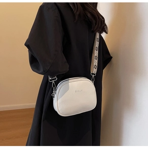 Detail of white lychee pattern crossbody bag with wide patterned strap and silver hardware