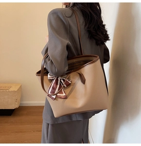 Detail of beige pebble leather tote bag with silk scarf on handle for daily commute