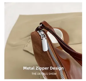 Detailed close-up of the silver hardware zipper on a brown suede and leather tote bag
