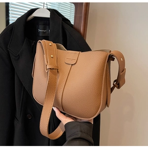 Détail d'un sac seau en cuir marron avec texture grainée et bandoulière réglable