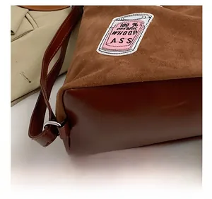 Detail showing precise stitching on brown suede and leather tote bag with embroidery