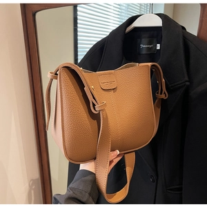 Gros plan du sac seau bandoulière en cuir grainé marron avec texture et bandoulière large