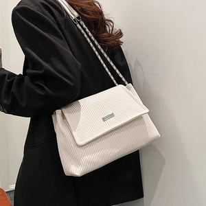 Chic beige corduroy tote bag with metal chain strap and flap closure shown on model