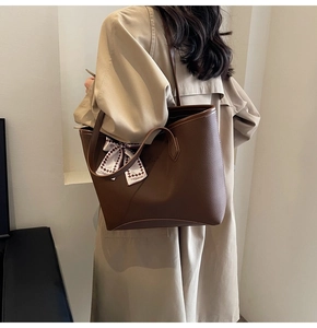 Detail view of large brown tote bag with lychee texture and fashion ribbon on handle