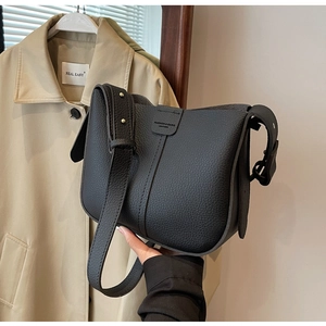 Détail du sac seau noir en cuir grainé avec coutures et bandoulière à rivets