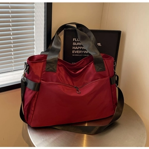 Détail du sac de voyage bordeaux en tissu Oxford avec texture étanche et larges anses noires