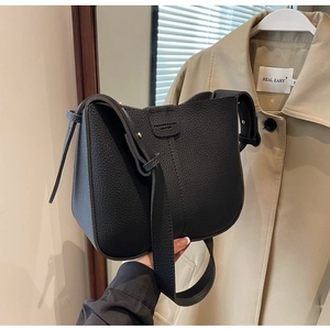 Détail du sac seau noir en cuir grainé avec logo mode et bandoulière large