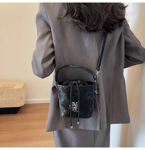 Détail d'un sac seau vintage noir avec texture marbrée argentée porté par un modèle