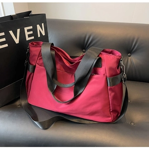 Détail macro du grand sac de voyage en nylon magenta avec poignées noires et bandoulière