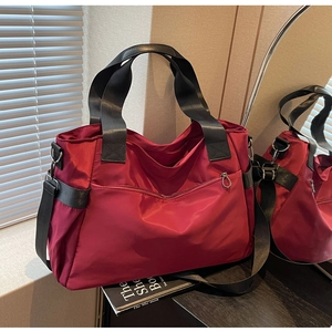 Détail d'un grand sac de voyage en nylon rouge foncé avec des sangles noires robustes