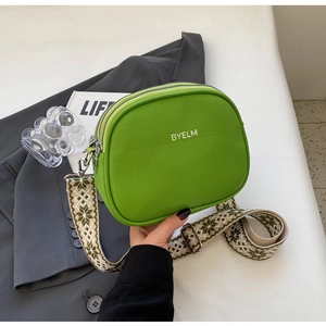 Close-up of green leather crossbody bag with embroidered ethnic style wide strap