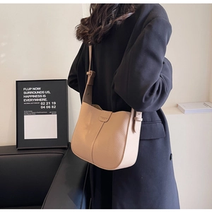 Détail d'un sac seau beige en cuir porté avec un manteau d'hiver long et noir