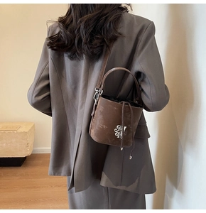 Vue arrière du sac seau en cuir marron avec logo argenté et cordon sur modèle