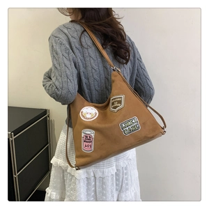 Detail view of large brown vintage tote bag with retro embroidered patches on soft leather