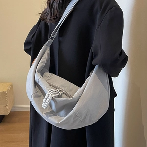 Minimalist light grey crescent nylon shoulder bag with woven rope detail and adjustable strap