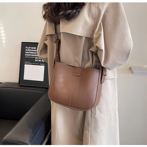Détail du sac seau marron café avec texture litchi et bandoulière élégante