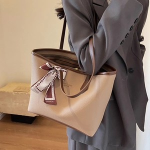 Large beige leather tote bag with dark brown straps and silk scarf on a model