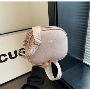 Detail view of pink lychee leather crossbody bag with geometric wide strap and silver zippers