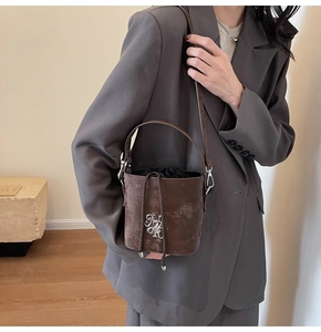Détail d'un sac seau vintage marron foncé avec logo métallique et cordon de serrage